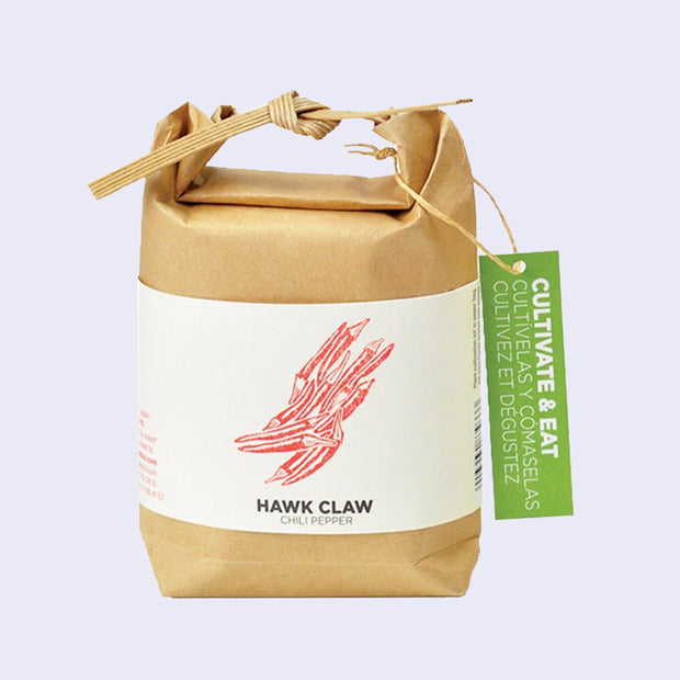  Brown paper sack, folded and tied with a paper tie and a green hang tag that reads "Cultivate & Eat". Wrapped around is a cream sheet, with an illustration of red chilli peppers. "Hawk Claw Chili Peppers" is written on the bottom.