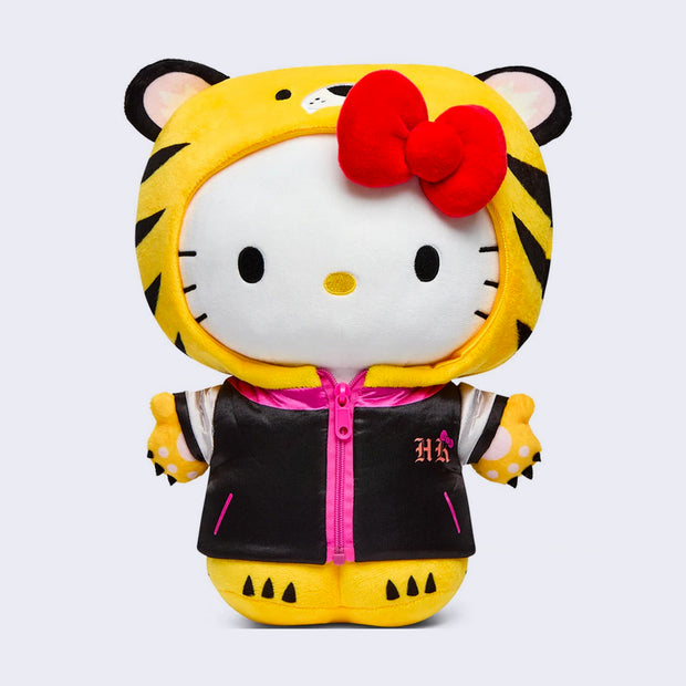 Plush of Hello Kitty, wearing a full body tiger costume, that goes over hear head like a hood, leaving her face revealed. She also wears a black satin style jacket with pink accents.