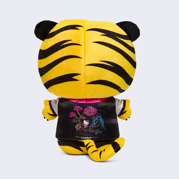 Back of Hello Kitty plush, wearing a full body tiger costume, that goes over her head like a hood. She also wears a black satin style jacket with a Japanese style illustration of a tiger, cherry blossom trees and Hello Kitty on the back of the jacket.