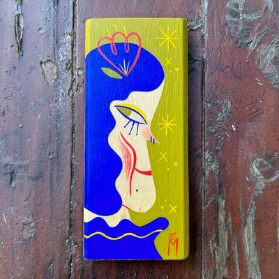 Olive green painted vertical rectangle piece of wood, with an illustration of a long faced blue haired girl looking off to the side.