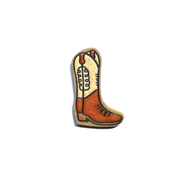 Stoneware die cut tile of a simple brown cowboy boot, facing to the right. The upper half of the boot is cream colored with a squiggle line design.