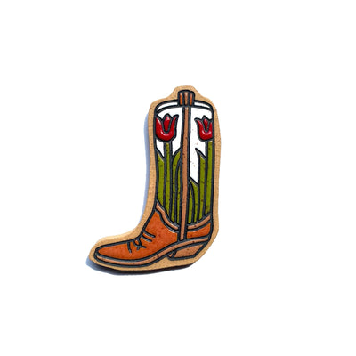 Stoneware die cut tile of a simple brown cowboy boot, facing to the left. The shaft of the boot is white with two stemmed red tulip, one on either side of the center piping.