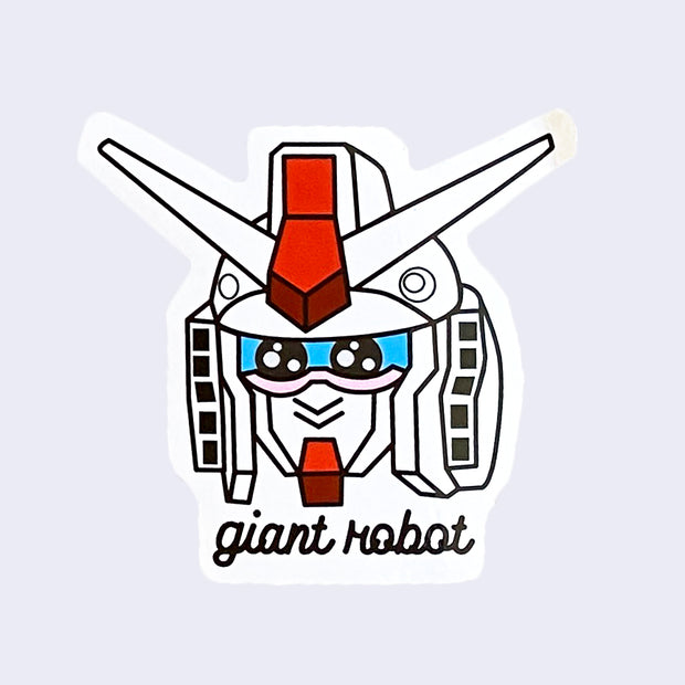 White cut out sticker of a cartoon Gundam robot head, with red and black accents. It has kawaii style eyes. "Giant Robot" is written in lowercase black cursive below the design.