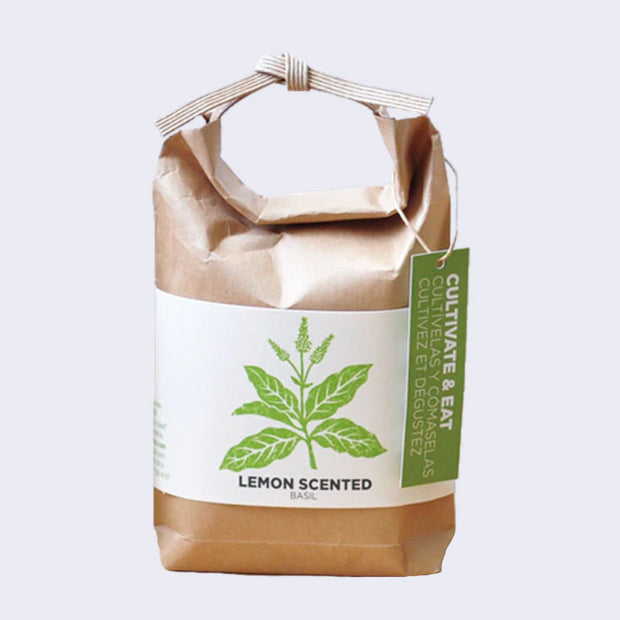 Brown paper sack, folded and tied with a paper tie and a green hang tag that reads "Cultivate & Eat". Wrapped around is a cream sheet, with an illustration of basil leaves. "Lemon Scented Basil" is written on the bottom.