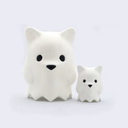 Large vinyl simplified white bear head figure, with small round black eyes and a small black triangle nose. It has points around its neck that hold it up, like the bottom of a collar. It stands next to a miniature version of the same design.