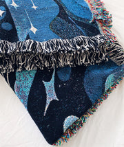 Close up photo of folded tapestry blanket, showing the intentional side fraying.