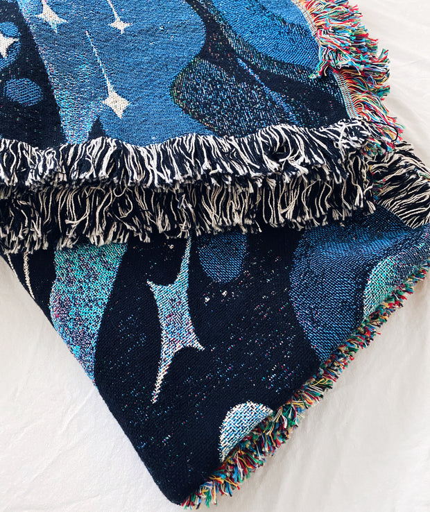 Close up photo of folded tapestry blanket, showing the intentional side fraying.