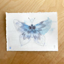 Watercolor illustration of a blue butterfly with its wings spread out flat.