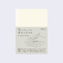 Cream colored notebook cover with a paper sleeve wrapped around with details about the notebook in English and Japanese.