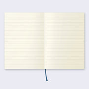 Open page spread of the notebook displaying lined cream colored paper and a dark ribbon for place marking.