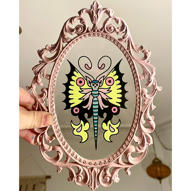 Small painting of a tattoo style yellow, pink and black butterfly on a clear acrylic sheet in a very ornate pink frame.