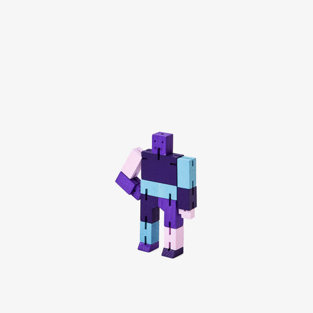Wooden robot made of square-like shapes, standing with an arm on its hip. It is various shades of purple and some light blue.
