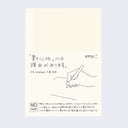 Cream colored notebook cover with a paper sleeve wrapped around with details about the notebook in English and Japanese.