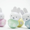 A plastic Miffy figure wearing a pastel green shirt with a rounded bottom, wobbling slightly on a tilt. More wobble Miffy figures are out of focus in the background.