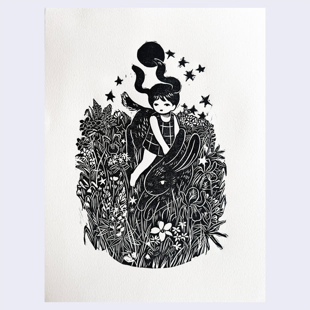 Black ink woodcut on white paper of a young girl with long pigtails, flying in the wind to resemble bunny ears, riding atop of a large bunny through a field of flowers and tall grass. Behind her is a full moon and some decorative stars.
