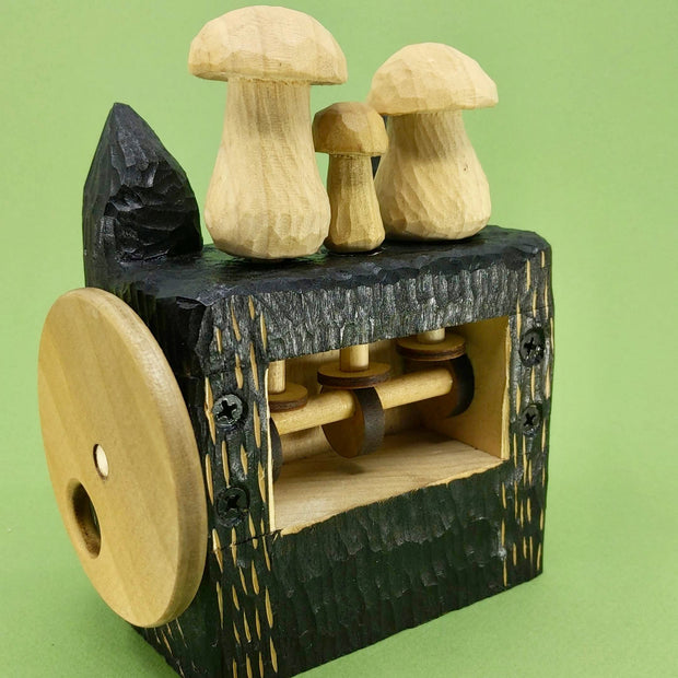 Back angle of a wooden, block shaped black wolf head with small details carved exposing the natural wood, there are 3 wooden mushrooms atop its head. The interior mechanism are exposed in the back, the woodwork allowing for the movement of the mushrooms up and down. m