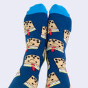 Front view of a model's feet wearing chubby cartoon boba socks. A fat red straw sticks out of its lid.