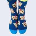 Front view of a model's feet wearing chubby cartoon boba socks. The sock's main color is dark blue. The smiling boba cups are beige.