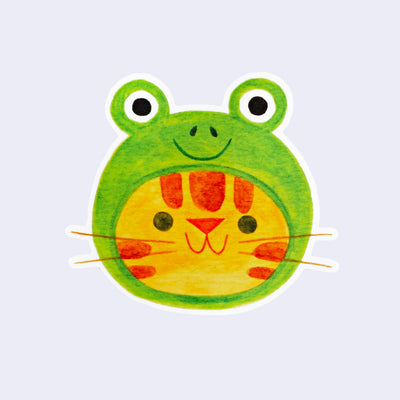 Die cut sticker with white border of a smiling orange tabby cat head wearing a hat that looks like a frog's head.