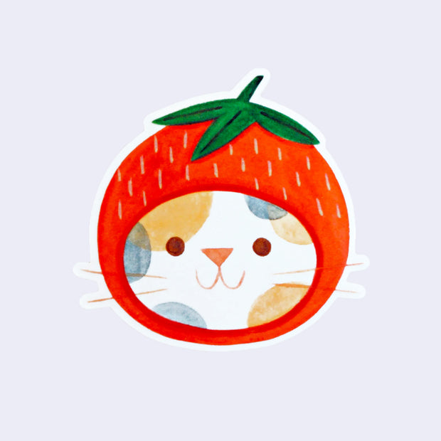Die cut sticker of a white calico cat head, smiling and wearing a strawberry hat around its head like a hood.