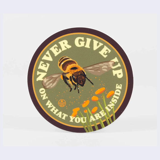 Circular sticker with brown and yellow outline border and sage green background. A honeybee pollinates orange poppies. "Never give up on what you are inside" is written in bold stylized font.