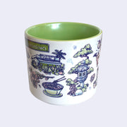  White ceramic mug with a metallic green interior and various illustrations on it, all within a color scheme of blue, pink, white and green. Illustrations include an exterior of a plant nursery, a bowl of ramen, a stone lantern with a tree behind it, and a taiyaki.