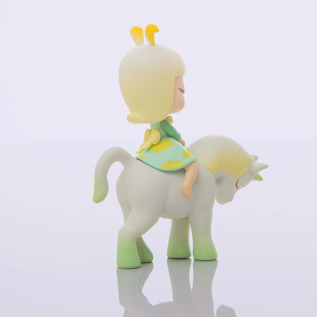 Vinyl figure of a young girl with blonde hair and bunny ears on a pastel white to green ombre unicorn, both with their eyes closed.