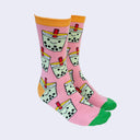 Side view of a model's feet wearing chubby cartoon boba socks. The heel area and trim are a marigold color. The toe area is bright green.