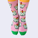 Front view of a model's feet wearing chubby cartoon boba socks. A fat red straw pokes out of the boba cup's lid.