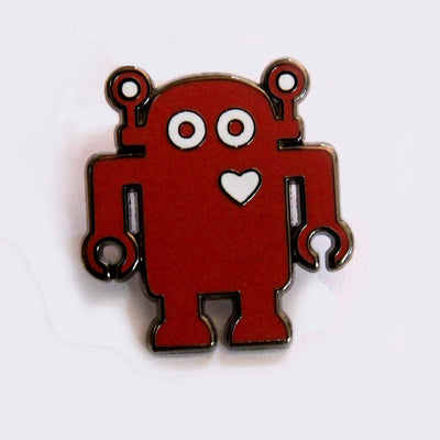 Enamel pin of a red robot with a silver outline and a white heart on its upper right chest.