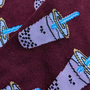 Close up of the smiling boba pattern. The boba are slightly pixelated due to the knitted fabric. A bright blue straw pokes out of the boba's lid.