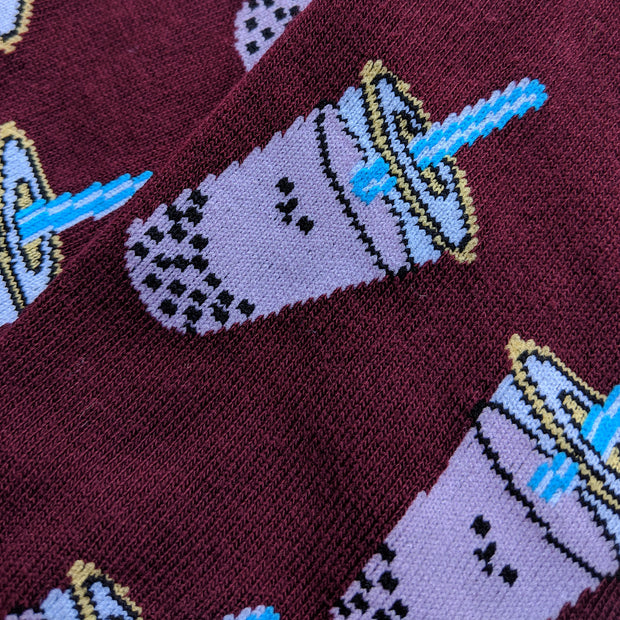 Close up of the smiling boba pattern. The boba are slightly pixelated due to the knitted fabric. A bright blue straw pokes out of the boba's lid.