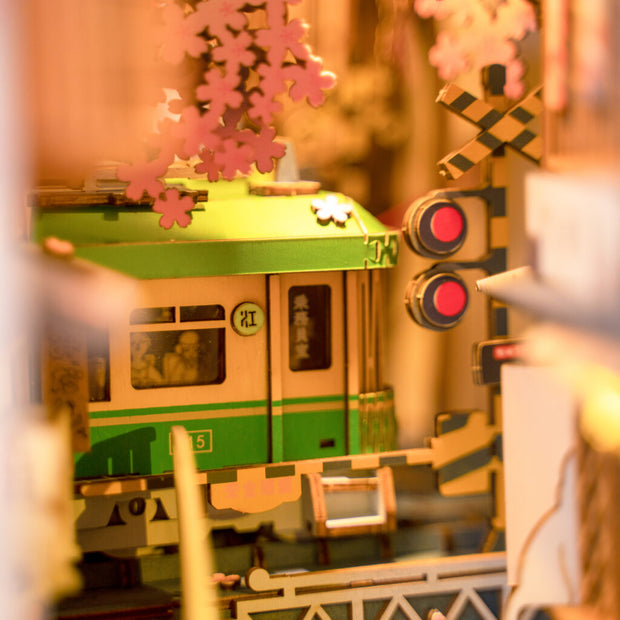 Close up of finished model kit, displaying a green subway car riding through many cherry blossom trees.