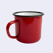 Bright red enamel mug. Rim of the mug is lined black with a white interior.