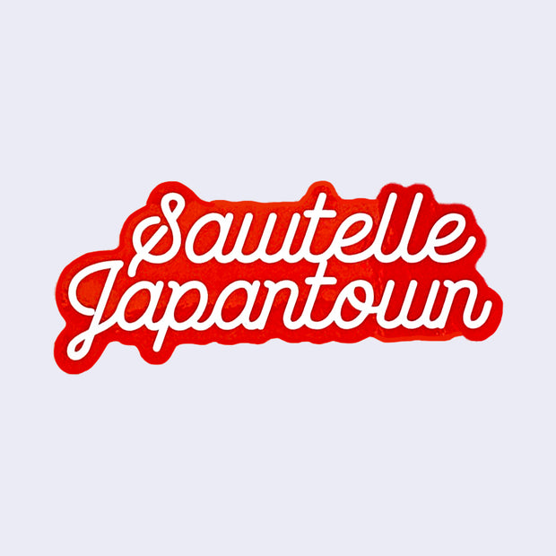 Red cut out sticker with "Sawtelle Japantown" written in white, cursive font. "Sawtelle" is stacked above "Japantown."