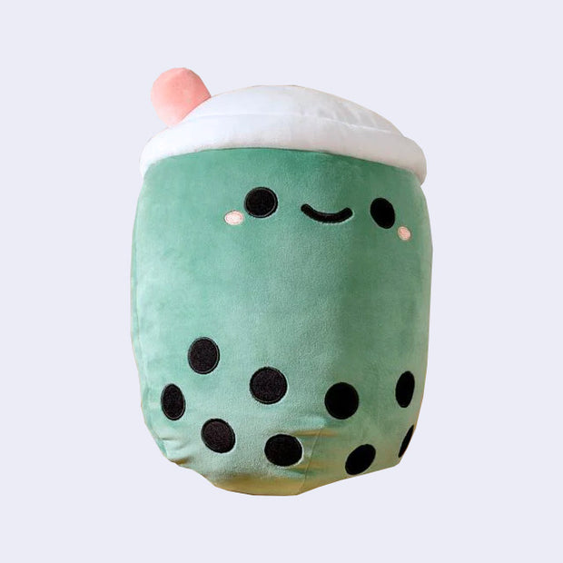 Rounded squishy sage green plush shaped like a boba tea cup, with a cute kawaii smile and a pink straw coming out of the top.
