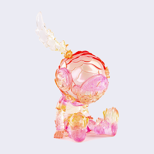 Semi transparent sculpted figure of a small person sitting with their hands at their side, legs out in front of them and wearing a scuba diving helmet with a feather coming out of the top. Figure is primarily pink with orange ombre elements.