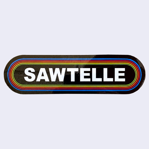 Long rounded corner rectangle sticker, black with the word "Sawtelle" written in bold, all caps white font in the center. It is surrounded by 6 thin lined borders, each a different color of the rainbow.