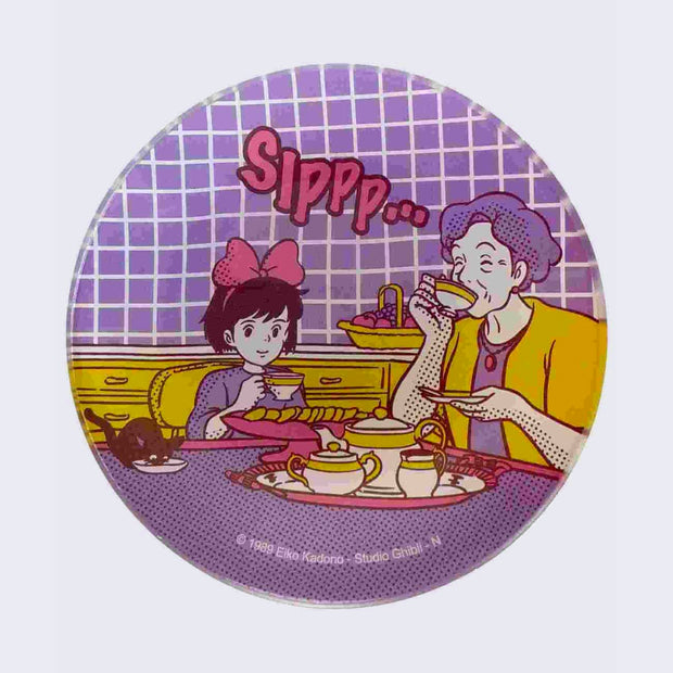 Round glass dish with a colorful purple, yellow and pink graphic of Kiki from Kiki's Delivery Service sitting at a kitchen table with an older woman, drinking tea and smiling.