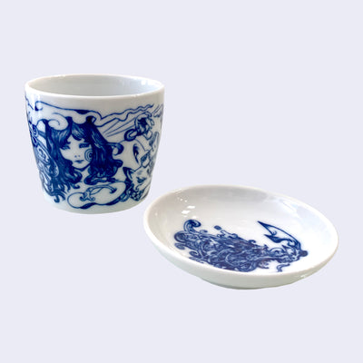 White ceramic cup and saucer set with dark blue illustration on each. The cup features a wrap around illustration, with the front featuring a long haired girl with many swirls around her. The plate features a multitude of swirls.