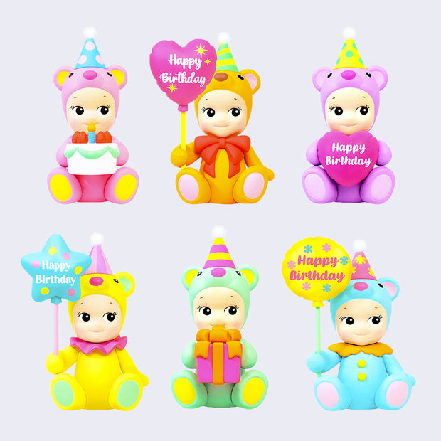 6 different designs of Kewpie babies dressed as sitting teddy bears. Colors include: pink, orange, purple, yellow, mint or blue and each is holding a different birthday object. Either a balloon, cake or present.