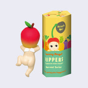 Vinyl figure of a small Kewpie angel baby, nude with tiny wings on its back and an apple around its head like a hood hat. It is only visible from behind, where it appears to be climbing up something. It is next to its display box which is yellow and says "Sonny Angel Hippers Harvest Series"
