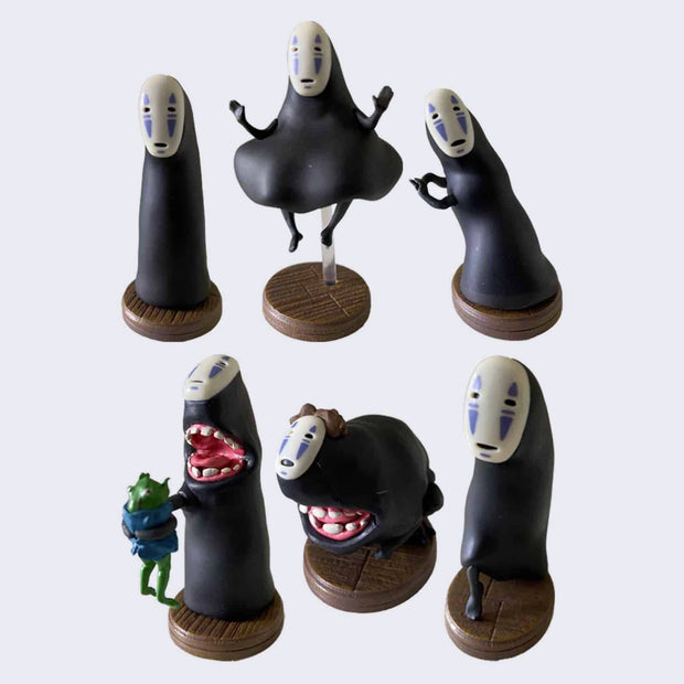 6 differently designed vinyl figures of the character No Face from Spirited Away. Poses include, standing upright, levitating, leaning to the left, standing with open mouth while holding a green frog, crouching with mouth open and tip toeing. 