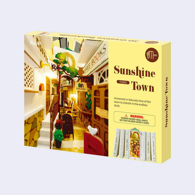 Product packaging of a 3D puzzle kit to build a bookend, with scenery of an alleyway containing bookshops and other shopping center visuals.
