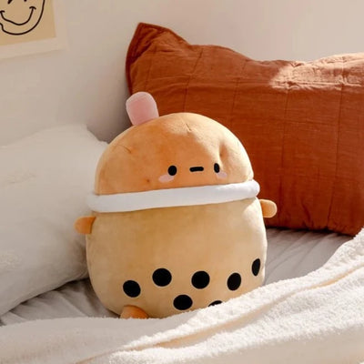 A squishy plush shaped like a potato character, dressed up as a cup of boba tea with a pink straw.