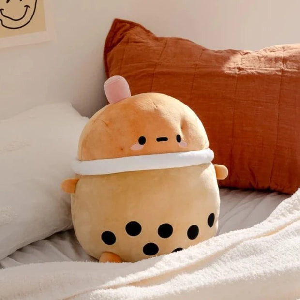 A squishy plush shaped like a potato character, dressed up as a cup of boba tea with a pink straw.