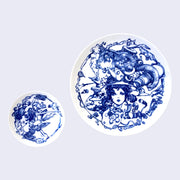 2 white ceramic plates with blue designs. Smaller plate features illustration of a woman facing away, her body breaking down into many mechanical parts. The larger plate features a series of illustrations of a concerned looking woman wearing a hat, with many animals building off of her head and many mechanical parts coming from her neck.