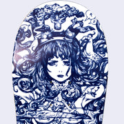 Close up of white skateboard deck with intricate blue line art illustration. Close up displays a woman with an anguished expression, with splayed out hair and two birds coming out of a headband. Her arms are raised to her head and her body is tattooed.