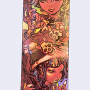 Close up of two intricately illustrated women, one holds a bear trinket in her hand and has skulls near her body, the other woman wears an intricate helmet and looks to the side indifferently.