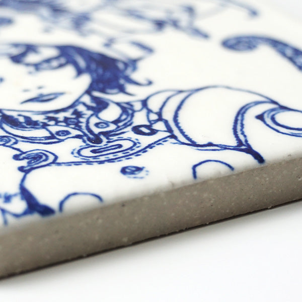 Close up of ceramic white tile with a dark blue line art illustration on it.